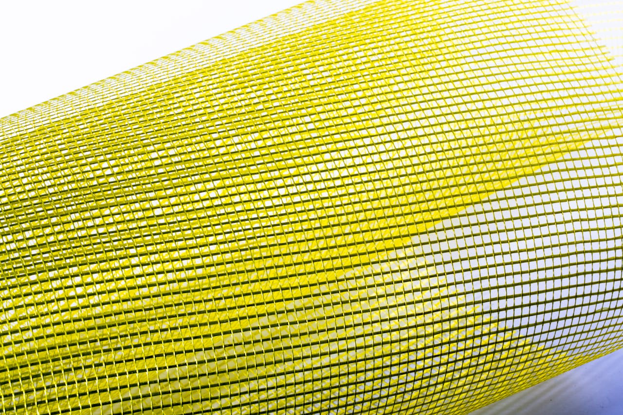 Abstract image of a yellow mesh roll with a grid pattern on a clean white background.