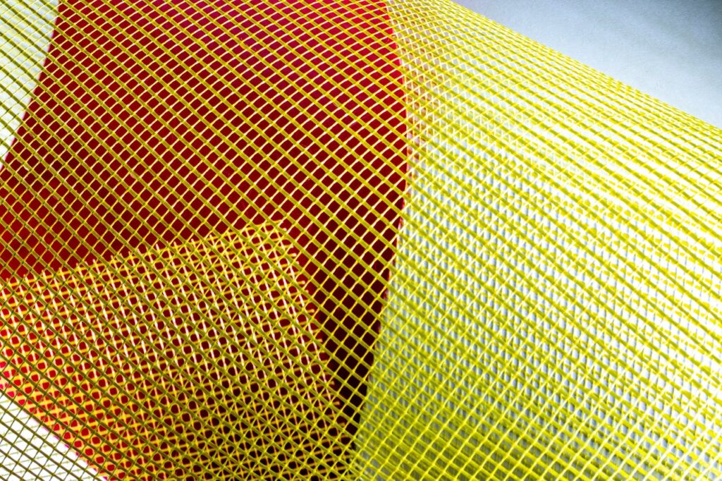 Close-up of a colorful mesh pattern featuring yellow and red hues, creating a vibrant abstract texture.